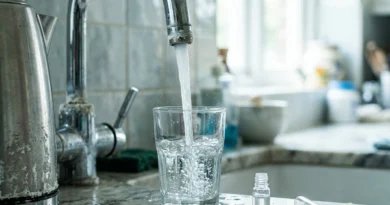 Rubinetto con incrostazioni di calcare che riempie un bicchiere, esempio di durezza acqua elevata in cucina